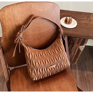 Detailed matelassé pleated leather surface and knot bow on a brown underarm bag