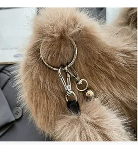 Gros plan sur les ferrures dorées et le grelot d'un sac en peluche marron