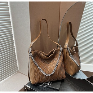 Detail of a brown pleated tote bag with sleek silver chain and thin leather shoulder strap
