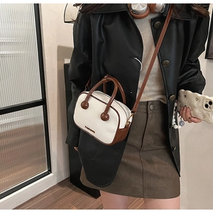 Detail der Retro-Umhängetasche in Beige mit braunen Kontrasten und runden Griffhalterungen