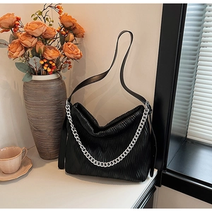 Detail of black pleated cloud bag with silver chain strap and soft leather texture