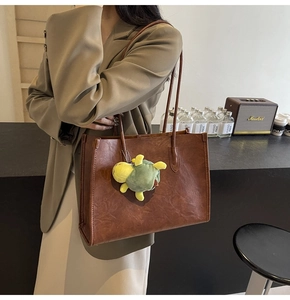 Dettaglio di una borsa tote vintage marrone con ciondolo a tartaruga sulla modella