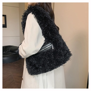 Side view of a large black plush shoulder bag with metal zipper on a model in white coat