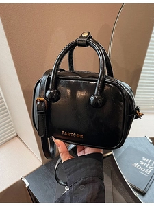 Schwarze glänzende Schultertasche aus Leder mit goldenem Logo und runden Griffelementen