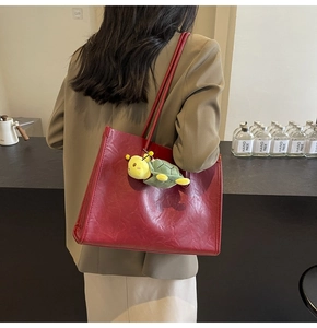 Dettaglio della borsa tote in pelle rossa con texture vintage e ciondolo a tartaruga