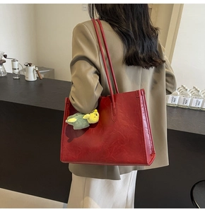 Vista dettagliata di una borsa tote in pelle rossa con un ciondolo a forma di tartaruga