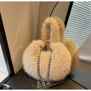 Détail d'un sac peluche beige avec une bandoulière en chaîne de perles métalliques épaisses