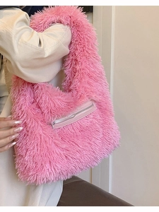 Pink plush tote bag with front zipper pocket shown in a stylish over-the-shoulder view