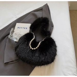 Détail d'un sac à main en fausse fourrure noire avec chaîne à billes argentées sur veste