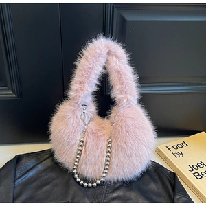 Détail du sac en peluche rose avec chaîne décorative en perles argentées sur cuir noir