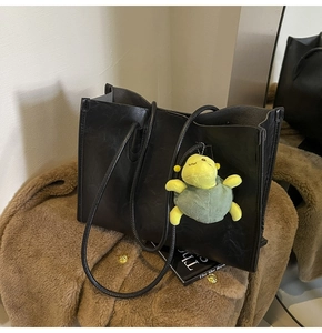Dettaglio della borsa tote in ecopelle nera con un simpatico ciondolo a forma di tartaruga verde