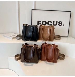Four retro bucket bags in black, tan and brown with wide geometric patterned straps