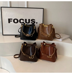 Macro view of minimalist bucket bags in four retro colors with gold chain details