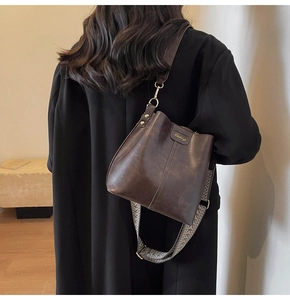 Close-up of retro dark brown bucket bag with geometric woven wide shoulder strap details