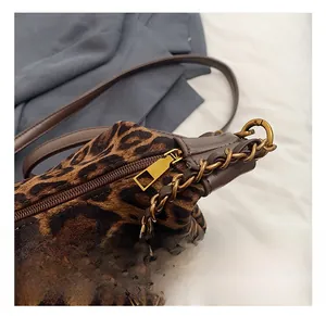 Close-up of golden hardware and leather strap on a leopard print shoulder bag
