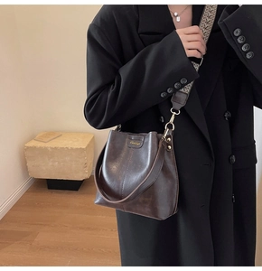 Détail d'un sac seau marron foncé avec cuir texturé et bandoulière tissée