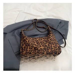 Close-up of leopard print crossbody bag with brown leather trim and gold chain detail