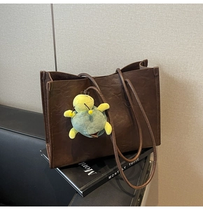 Dettaglio della texture della borsa tote marrone con venature e ciondolo a tartaruga