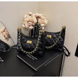 Dettaglio borsa a mezzaluna in pelle trapuntata nera con catena d'oro e fibbia metallica