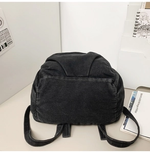 Detail view of the washed denim backpack back structure with wide shoulder straps