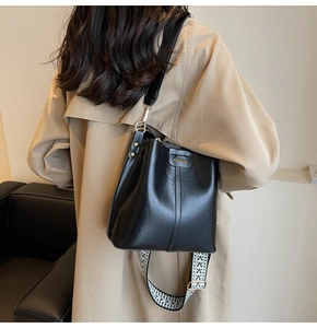 Détail du sac seau noir avec bandoulières élégantes à motifs et en similicuir lisse