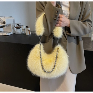 Détails de la texture d'un sac demi-lune en fausse fourrure jaune avec chaîne perlée