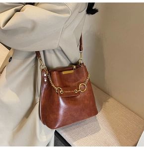 Detail view of a vintage brown bucket bag with gold chain and FASHION & YM logo label