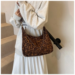 Detail der Damen-Umhängetasche mit Leopardenmuster und goldener Kette am Modell