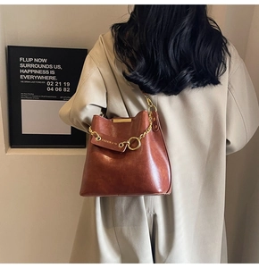 Detail of brown vintage bucket bag with gold chain on model in trench coat