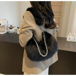 Détail d'un sac à épaule en fausse fourrure noire avec bandoulière chaîne argentée