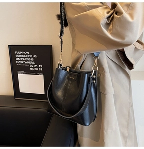 Détail du sac seau noir avec garnitures dorées et bandoulière large à carreaux