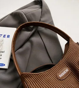 Detail of coffee brown pleated shoulder bag with a fixed leather handle and fashion label