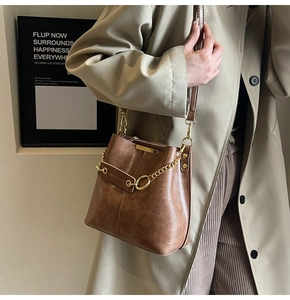Detail shot of vintage brown leather bucket bag with chunky gold chain and strap