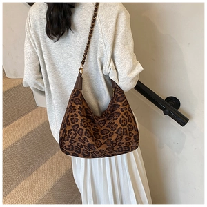 Detail der hobo-tasche mit leopardenmuster und goldener metallkette mit lederriemen