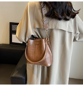 Brown leather bucket bag with geometric strap styled on a khaki trench coat