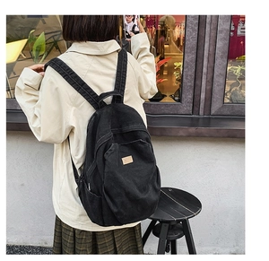 Detailed macro view of the black canvas backpack with a brown leather logo patch
