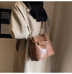 Close-up of retro brown bucket bag with metal chain and adjustable leather strap detail