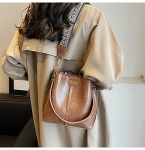 Gros plan sur un sac seau marron rétro avec une large bandoulière tissée ethnique