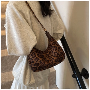 Detail of leopard print shoulder bag with metal chain strap worn by a model
