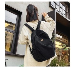 Close-up of black canvas backpack showing durable texture and leather brand logo patch