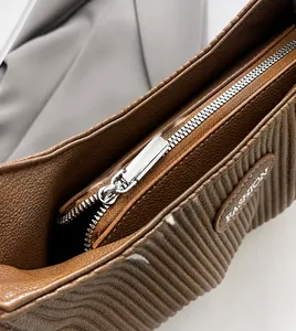 Detail of smooth metal zipper and pebbled brown leather texture on handbag