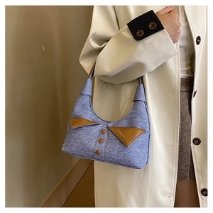 Détail du sac à bandoulière bleu avec design à revers, pattes en cuir marron et boutons
