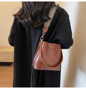 Detail of vintage brown bucket bag with ethnic woven strap and oily leather texture