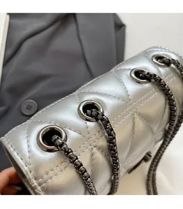 Detail of silver metallic quilted bag with thick chain strap and textured diamond pattern
