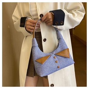 Gros plan d'un sac à main rétro en denim et cuir porté par un mannequin chic