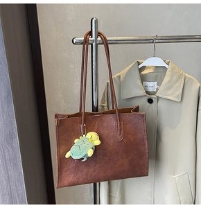 Dettaglio di una borsa tote in pelle marrone vintage con charm a forma di tartaruga