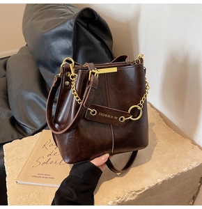Close-up of a vintage dark brown bucket bag with gold chain and FASHION & YM tag details