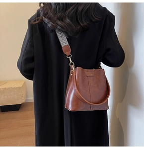 Brown bucket bag detail showing the retro PU texture and colorful woven shoulder strap