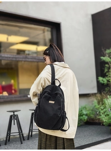 Close-up of lightweight black denim backpack showing stylish texture and brand label