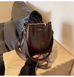 Detail of retro brown bucket bag featuring wide ethnic style woven strap and gold hardware